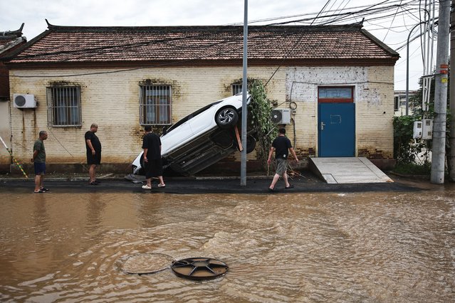 Four men look at a car whased away by flooding in Taishitun, in the district of Miyun, Beijing, China, 29 July 2025. The floods brought on by the rains in past days in Beijing resulted in the deaths of thirty people and the relocation of over 80,000 others. (Photo by Andrés Martínez Casares/EPA)