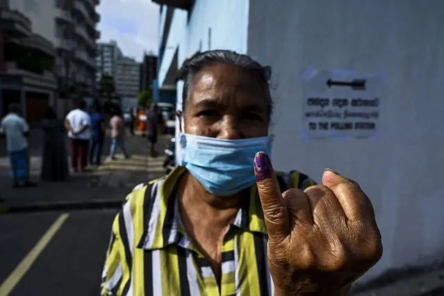 A voter wearing a facemask shows her inked finger after casting her ballot in the parliamentary election outside a polling station in Colombo August 5, 2020. Sri Lankan voters cast their ballots on August 5 for a new parliament as the ruling Rajapaksa brothers seek a fresh mandate to cement their grip on power. (Photo by Ishara S. Kodikara/AFP Photo)