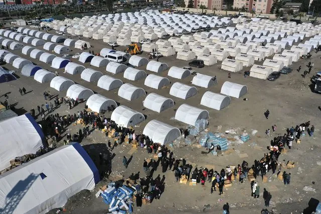 People who lost their houses in the devastating earthquake, lineup to receive aid supplies at a makeshift camp, in Iskenderun city, southern Turkey, Tuesday, February 14, 2023. Thousands left homeless by a massive earthquake that struck Turkey and Syria a week ago packed into crowded tents or lined up in the streets for hot meals as the desperate search for survivors entered what was likely its last hours. (Photo by Hussein Malla/AP Photo)