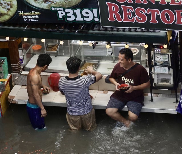 Filipino residents eat food in floodwater in Las Pinas, Philippines, 22 July 2025. On 21 July, the Philippine weather bureau was monitoring two low-pressure areas that could develop into tropical cyclones, as Typhoon Wipha exited the country after leaving at least five people dead. (Photo by Francis R. Malasig/EPA)