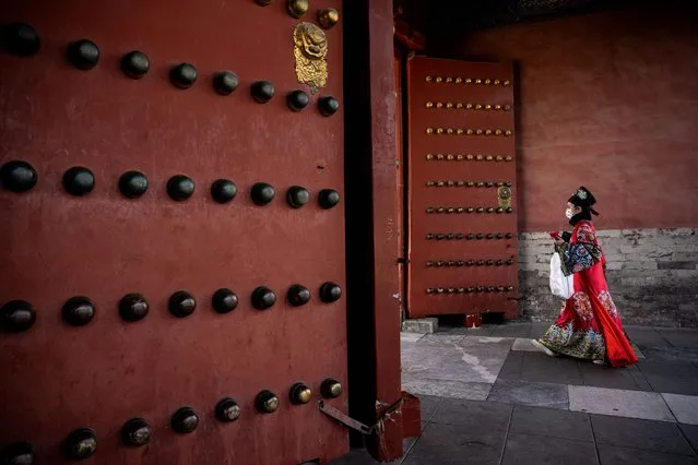 A woman wearing traditional clothes walks past the entrance of the Forbidden City in Beijing on March 1, 2023. (Photo by Noel Celis/AFP Photo)