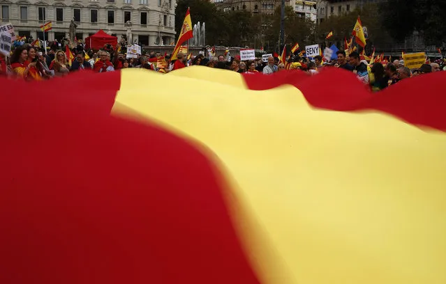 People wave a Spanish flag during a celebration for Spain's National Day in Barcelona, Spain, Wednesday, October 12, 2016. (Photo by Manu Fernandez/AP Photo)