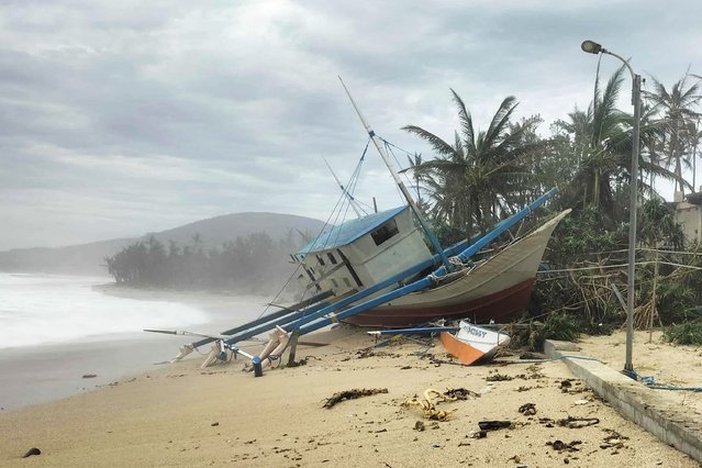 A fishing boat is seen washed ashore in Calayan island, Cagayan province on September 23, 2025, a day after Super Typhoon Ragasa hit the island. Ragasa had already toppled trees, torn the roofs off buildings and killed at least two people in a landslide while lashing the northern Philippines, where thousands sought shelter in schools and evacuation centres. (Photo by Cristy Gaffud/AFP Photo)