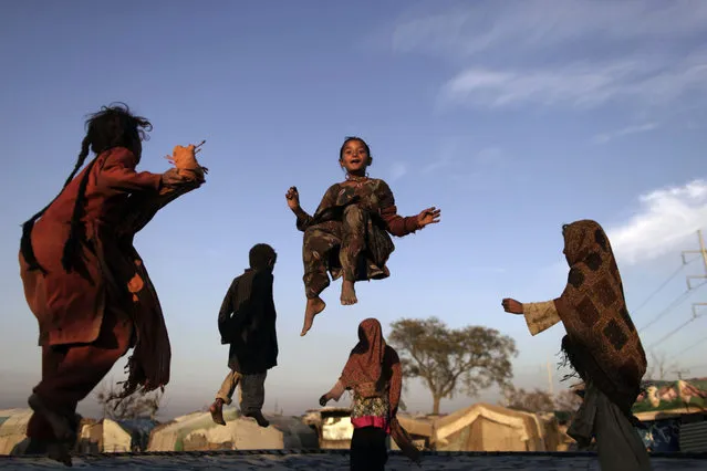 Pakistani children, who were displaced with their families by 2010 floods from a village in Pakistan's Sindh province, enjoy jumping on a trampoline, in a slum on the outskirts of Islamabad, Pakistan, Friday, February 8, 2013. (Photo by Muhammed Muheisen/AP Photo)