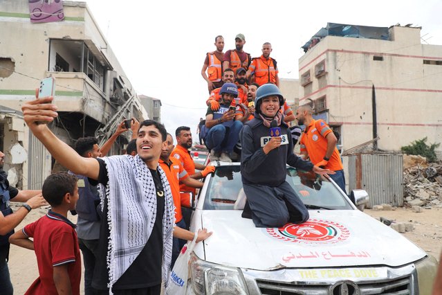 Al Jazeera reporter Nour Abu Rokba works, as Palestinian emergency personnel celebrate, after it was announced that Israel and Hamas agreed on the first phase of a Gaza ceasefire, in Gaza City, on October 9, 2025. (Photo by Ebrahim Hajjaj/Reuters)