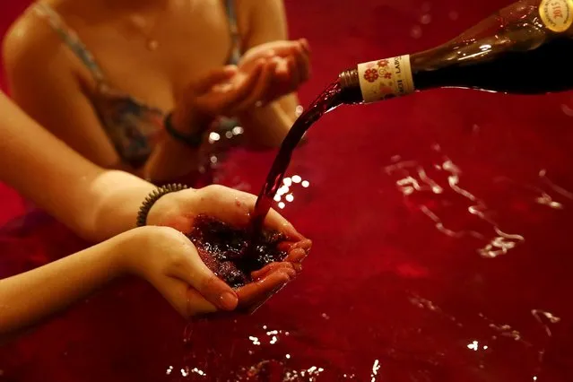 A man pours wine into the hand of a woman as she sits in a hot bath with coloured water representing wine at the Hakone Kowaki-en Yunessun spa resort during an event marking Beaujolais Nouveau Day in Hakone west of Tokyo, November 19, 2015. (Photo by Thomas Peter/Reuters)