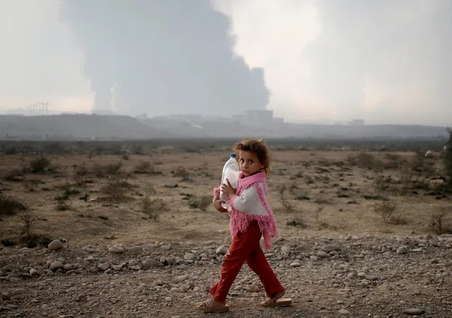 A newly displaced girl holds a bottle as she walks near a check point in Qayyara, east of Mosul, Iraq October 26, 2016. (Photo by Goran Tomasevic/Reuters)