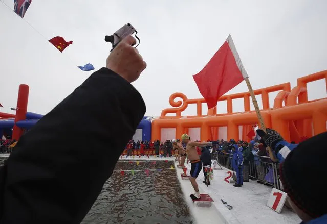 Officials hold a gun and flag as swimmers prepare to dive into a pool carved into the thick ice covering the Songhua River during the Harbin Ice Swimming Competition in the northern city of Harbin, Heilongjiang province January 5, 2015. (Photo by Kim Kyung-Hoon/Reuters)