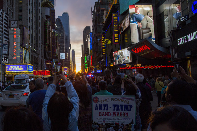 People take pictures of the phenomenon known as Manhattanhenge on Times Square 42nd Street on May 30, 2018 in New York City. Manhattanhenge, or the Manhattan Solstice, occurs twice a year when the sun is aligned with the east-west streets of the main street grid of Manhattan (Photo by Eduardo Munoz Alvarez/Getty Images)