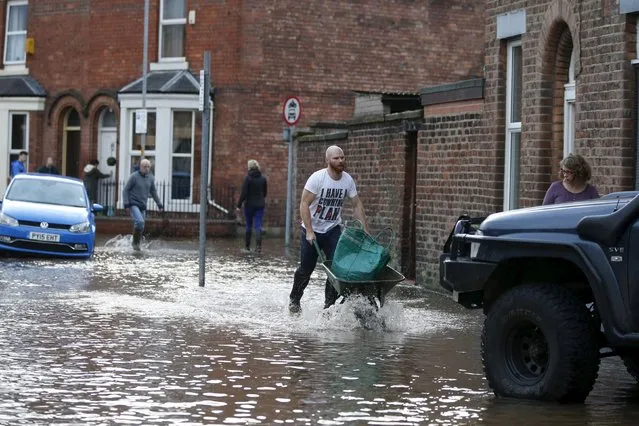 Residents move their belongings through flood waters in the Warwick Road area of Carlisle, Britain December 6, 2015. (Photo by Phil Noble/Reuters)
