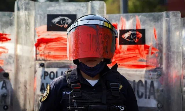 A riot police officer is seen after her helmet visor was painted red by a member of a feminist collective during a protest against gender and police violence, in Mexico City, Mexico on November 11, 2020. (Photo by Toya Sarno Jordan/Reuters)