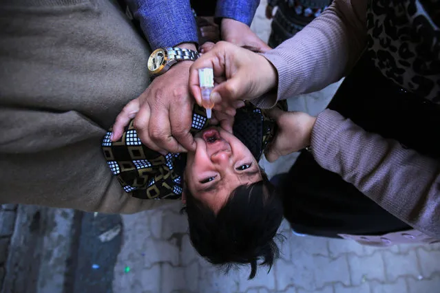 A health worker administers polio vaccine to children during a polio vaccination door-to-door campaign in Peshawar, Pakistan, 11 January 2021. A five-day national polio immunisation drive will start 11 January to vaccinate over 40 million children under the age of five across Pakistan. Around 285,000 polio frontline workers will visit parents and caregivers at their doorstep, adhering to strict COVID-19 precautionary measures and protocols while vaccinating children. These measures will include wearing a mask, using hand sanitizer, and maintaining a safe distance during the vaccination. (Photo by Bilawal Arbab/EPA/EFE)