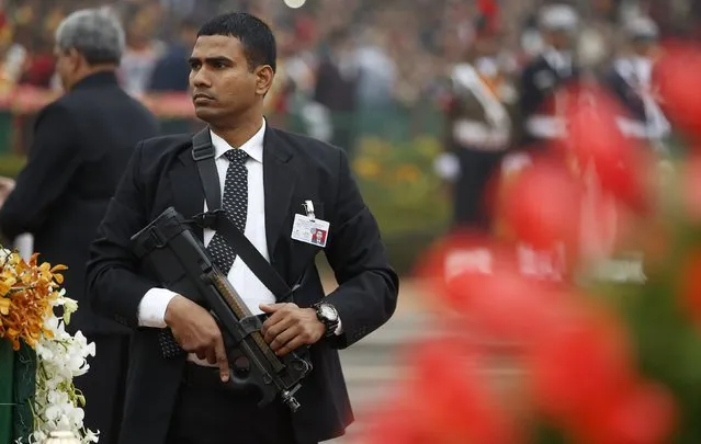 An Indian security officer guarding India's Prime Minister Narendra Modi and U.S. President Barack Obama keeps his weapon at the ready as he watches the crowd at the Republic Day parade in New Delhi January 26, 2015. (Photo by Jim Bourg/Reuters)