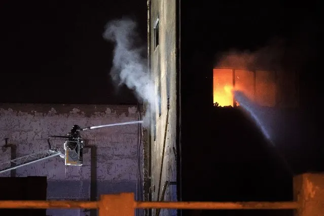 Firefighters work to extinguish a fire at a building in Badalona, Barcelona, Spain, Thursday, December 10, 2020. Authorities in northeastern Spain say a fire has raged through an abandoned building occupied by squatters in the city of Badalona, injuring at least 17 people, including two in critical condition. Firefighters say they rescued around 30 people from windows as the building burned late Wednesday. (Photo by Joan Mateu/AP Photo)