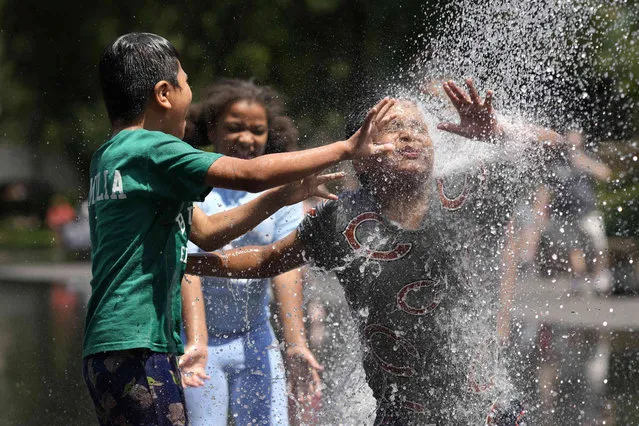 Kids enjoy the water spout at Crown Fountain in Chicago's Millennium Park as temperatures climbed into the 90's Fahrenheit, Friday, June 2, 2023, in Chicago. (Photo by Charles Rex Arbogast/AP Photo)