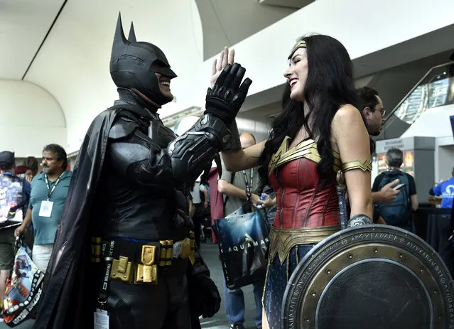 Armando Abarca, left, dressed as Batman, and Jessica Rose Davis, dressed as Wonder Woman, of Los Angeles, high five each other as they attend day one of Comic-Con International on Thursday, July 19, 2018, in San Diego. (Photo by Chris Pizzello/Invision/AP Photo)