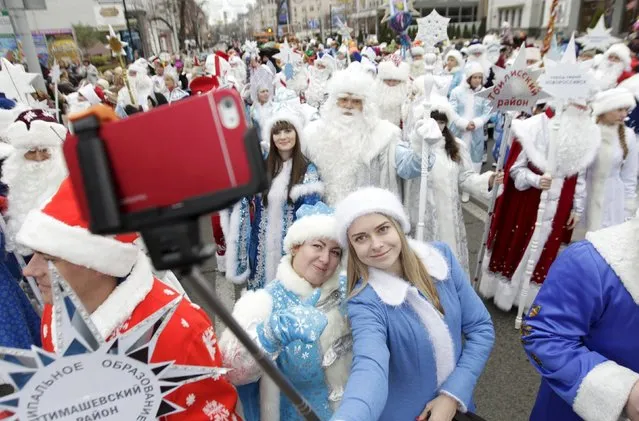 Participants take a selfie while people, dressed as Ded Moroz, his granddaughter Snegurochka and other characters, participate in a festive pre-holiday procession in Krasnodar, southern Russia, December 19, 2015. Ded Moroz (Old man Frost or Grandfather Frost) and Snegurochka (Snow Maiden) are the main characters of the New Year and Christmas holidays celebration in Russia and some other former Soviet states. (Photo by Eduard Korniyenko/Reuters)