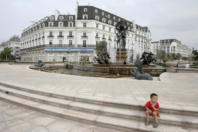A boy sits in front of a fountain at Tianducheng, a residential area on the outskirts of Hangzhou in east China's Zhejiang province September 1, 2007. After five years of development by Zhejiang Guangsha Co. Ltd., around 2,000 residents now live in Tianducheng, local media reported. (Photo by Aly Song/Reuters)