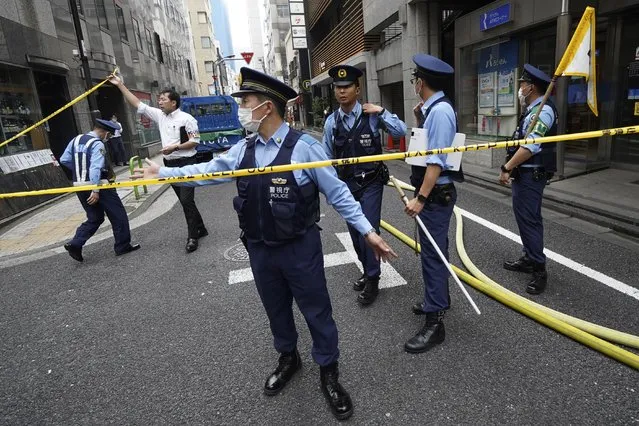 Police officers controls journalists near the scene of an explosion in a building Monday, July 3, 2023, in Tokyo. An explosion at a building in Tokyo’s commercial district of Shimbashi on Monday shattered windows and spewed smoke, according to media reports. (Photo by Eugene Hoshiko/AP Photo)