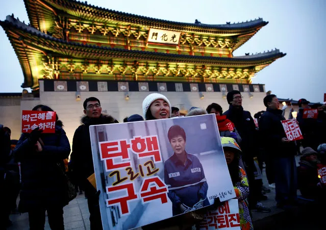 A woman holds a poster showing a computerized image of South Korean President Park Geun-hye during a protest calling Park to step down in Seoul, South Korea, November 26, 2016. The slogan reads, “Impeachment and arrest'”. (Photo by Kim Kyung-Hoon/Reuters)