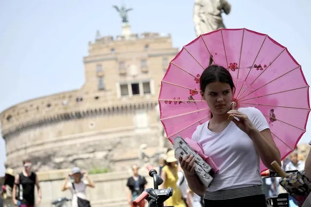 A woman carries an umbrella during a heat wave in Rome, Italy, 16 July 2023. Italy is facing the third heatwave of the summer on 16 July bringing record temperatures. The new heatwave is forecast to peak on 18 July, when temperatures in areas of southern Sardinian may reach 48 degrees Celsius, according to forecasts. On 15 July, the health ministry has put on red alert major Italian cities. (Photo by Massimo Percossi/EPA)