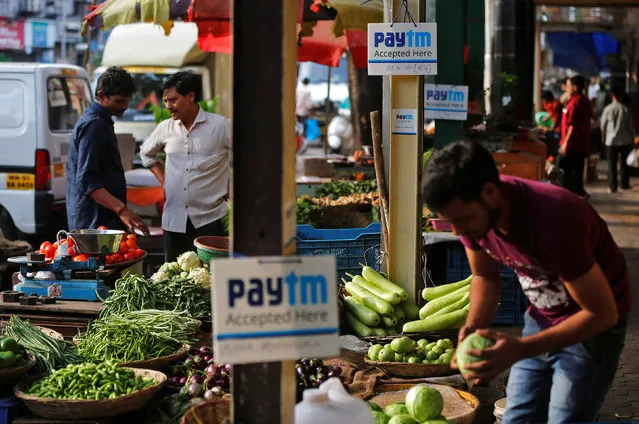 Advertisement boards of Paytm, a digital wallet company, are seen placed at stalls of roadside vegetable vendors as they wait for customers in Mumbai, India, November 19, 2016. (Photo by Shailesh Andrade/Reuters)