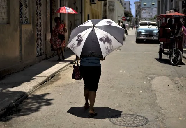A pedestrian shades herself with an umbrella in Havana, Cuba, Wednesday, July 5, 2023. The entire planet sweltered for the two unofficial hottest days in human record keeping Monday and Tuesday, according to University of Maine scientists at the Climate Reanalyzer project. (Photo by Ramon Espinosa/AP Photo)