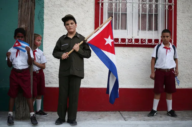 Children wait along a street for the ashes of Fidel Castro to pass during a three-day journey to the eastern city of Santiago de Cuba, in Bayamo, Cuba, December 2, 2016. (Photo by Edgard Garrido/Reuters)