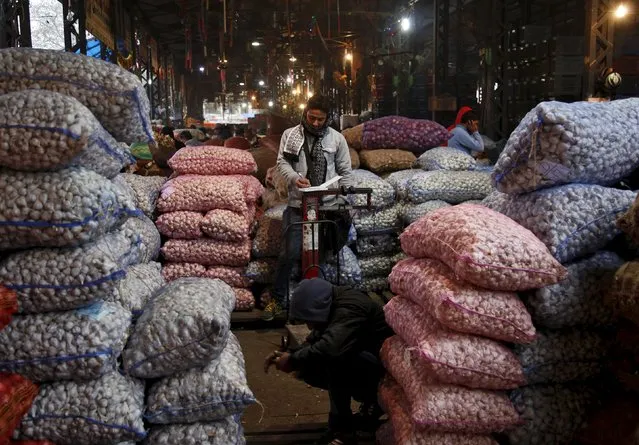 An accountant works next to the stacked sacks of garlic at a wholesale vegetable market in Chandigarh, India, January 14, 2016. India's wholesale prices fell for a 14th straight month in December, declining an annual 0.73 percent, driven down by tumbling oil prices, government data showed on Thursday. (Photo by Ajay Verma/Reuters)