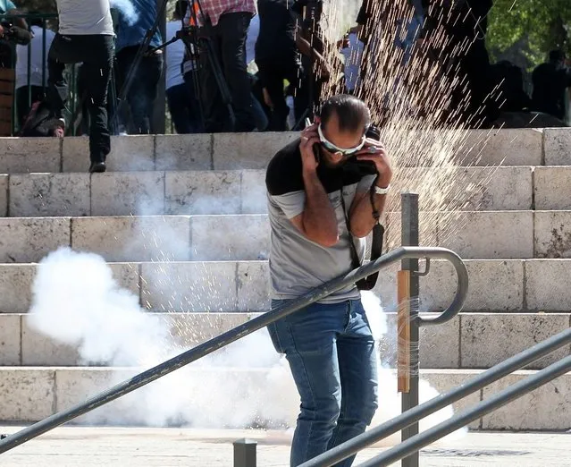 People react to a stun grenade fired by Israeli police officers during a demonstration held by Palestinians to show their solidarity amid Israel-Gaza fighting, at Jerusalem's Old City, May 18, 2021. (Photo by Ammar Awad/Reuters)