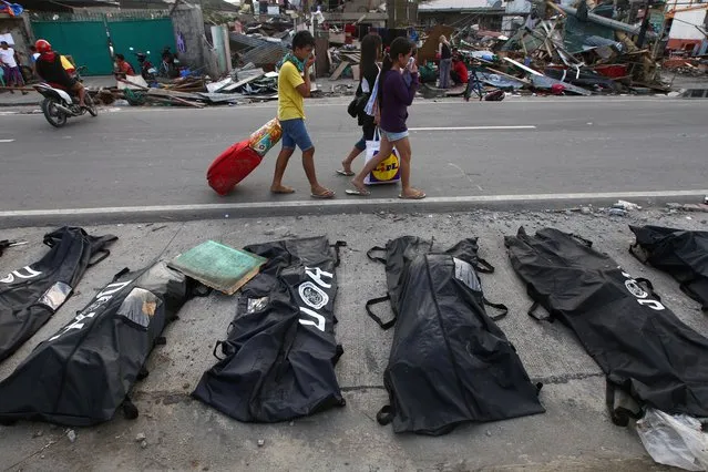 People cover their noses from the stench of dead bodies in an area affected by Typhoon Haiyan in Tacloban, Philippines, Wednesday, November 13, 2013. (Photo by Dita Alangkara/AP Photo)