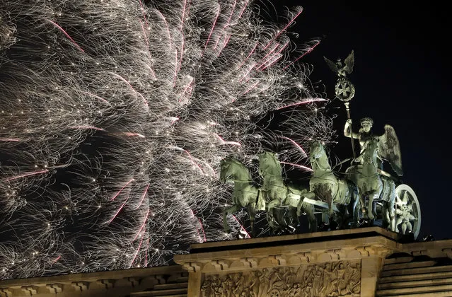 Fireworks light the sky above the Quadriga at the Brandenburg Gate shortly after midnight in Berlin, Germany, Tuesday, January 1, 2019. Hundred thousands of people celebrated New Year's Eve welcoming the new year 2019 in Germany's capital. (Photo by Michael Sohn/AP Photo)