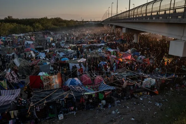 Migrants take shelter along the Del Rio International Bridge at sunset as they await to be processed after crossing the Rio Grande river into the U.S. from Ciudad Acuna in Del Rio, Texas, U.S. September 19, 2021. Picture taken with a drone. (Photo by Adrees Latif/Reuters)