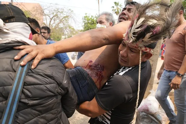 Indigenous protesters come to the aid of a wounded protester injured during clashes with police over the arrest of a tribal leader, the day after lawmakers approved a bill that criminalizes land invasions, in Asuncion, Paraguay, Thursday, September 30, 2021. The law affects several Indigenous communities who reside in improvised settlements pending the restitution of their lands. (Photo by Jorge Saenz/AP Photo)