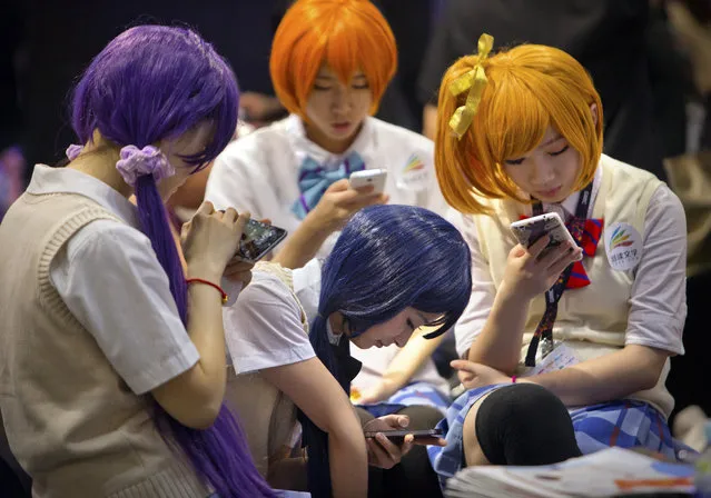 Models in costumes use their smartphones as they take a break at the Global Mobile Internet Conference in Beijing, Wednesday, April 29, 2015. Beijing's municipal government declared Wednesday as “Capital Internet Safety Day” as part of an effort to educate Chinese Internet users on avoiding fraud and identity theft online. (Photo by Mark Schiefelbein/AP Photo)