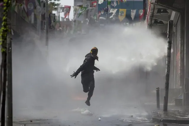 A masked protester runs away from a water cannon's jet during clashes with police in Okmeydani neighbourhood in Istanbul, Turkey, May 1, 2015. (Photo by Kemal Aslan/Reuters)