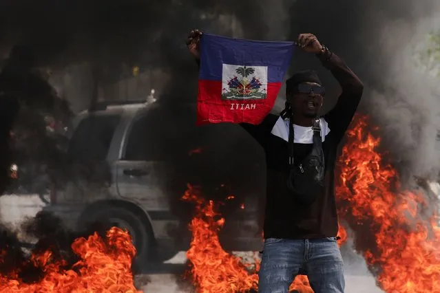 A demonstrator holds up a Haitian flag during a protest against Prime Minister Ariel Henry's government and insecurity, in Port-au-Prince, Haiti on March 1, 2024. (Photo by Ralph Tedy Erol/Reuters)