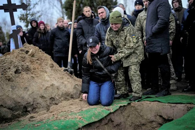 Anya Korostenska drops to her knees at the grave of her fiance Oleksiy Zavadskyi, a Ukrainian serviceman who died in combat on January 15 in Bakhmut, during his funeral in Bucha, Ukraine, Thursday, January 19, 2023. (Photo by Daniel Cole/AP Photo)