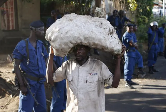 A man carrying a sack passes by policeman along a street in Bujumbura, Burundi, May 11, 2015. (Photo by Goran Tomasevic/Reuters)