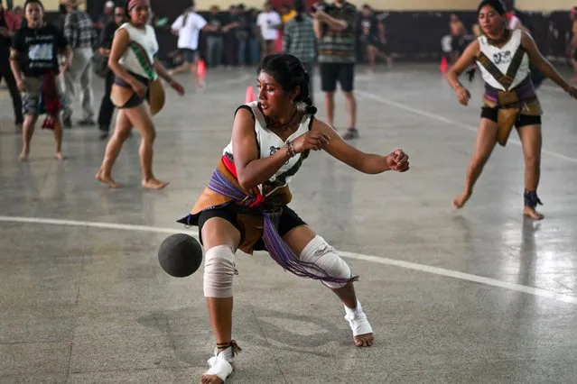 An indigenous woman kicks the ball during a Mayan ball game match in Tecpan, Guatemala on March 23, 2024. Dressed in shorts, girdle and uncovered torso, members of eleven teams from the Guatemalan indigenous departments of Chimaltenango, Quiche, Solola and Quetzaltenango, as well as one from El Salvador, commemorated the March equinox with a tournament of the ancestral Mayan ball game on Saturday. (Photo by Photo by Johan Ordonez/AFP Photo)