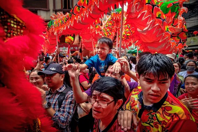 A child watches dragon and lion dancers perform during Lunar New Year celebrations at Binondo district, considered the world's oldest Chinatown, on February 10, 2024 in Manila, Philippines. Lunar New Year, also known as Chinese New Year, is celebrated around the world, and the year of the Wood Dragon in 2024 is associated with growth, progress, and abundance, as wood represents vitality and creativity, while the dragon symbolizes success, intelligence, and honor. (Photo by Ezra Acayan/Getty Images)