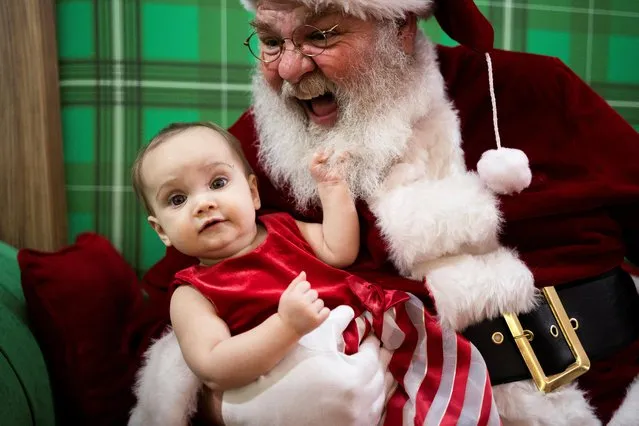 Aubrey Zimmermann, 9-months-old, poses for a photo with Santa at the Willow Grove Park Mall ahead of Christmas in Willow Grove, Pennsylvania, U.S. December 3, 2021. (Photo by Hannah Beier/Reuters)