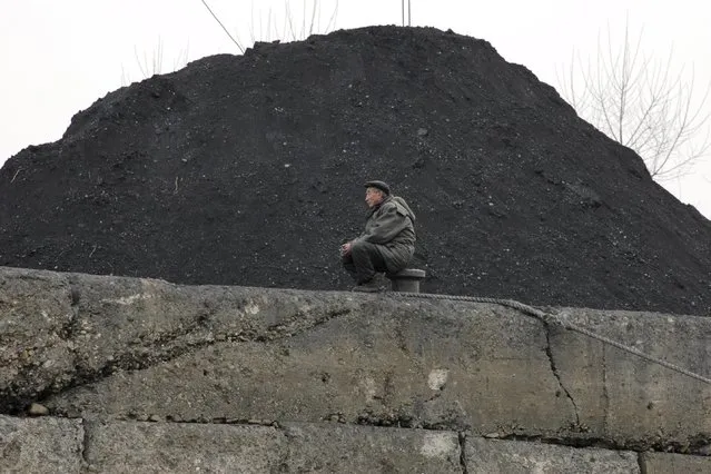 A North Korean man sits beside a pile of coal on the bank of the Yalu River in the North Korean town of Sinuiju in this December 16, 2006 file picture. (Photo by Adam Dean/Reuters)