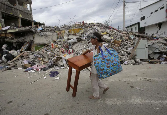 A woman carries a table through the street after an earthquake in Pedernales, Ecuador, Sunday, April 17, 2016. (Photo by Dolores Ochoa/AP Photo)