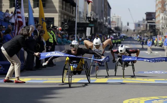 Marcel Hug, of Switzerland, breaks the tape ahead of Kurt Fearnley, of Australia, center, and Ernst Van Dyk, of South Africa, in the wheelchair division of the 120th Boston Marathon on Monday, April 18, 2016, in Boston. (Photo by Elise Amendola/AP Photo)