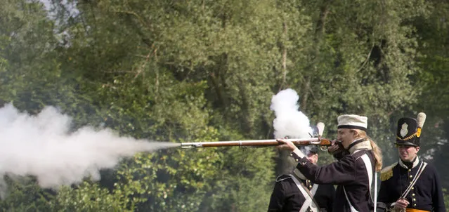 In this May 10, 2015, photo, the youngest member of a re-enactor group of the Belgian-Dutch 7th Battalion of the Line, Luca Scalzotto, 19, fires his weapon during a drill at a Napoleonic era living history camp in Elewijt, Belgium. The Belgian-Dutch living history group is coordinating their group for participation in the 200th anniversary of the Battle of Waterloo which will take place in June 2015. (AP Photo/Virginia Mayo)