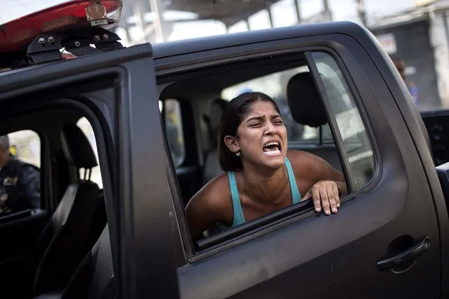 A woman screams after being detained during protests near the area recently occupied by squatters in Rio de Janeiro on April 11, 2014; she was later released. (Photo by Felipe Dana/Associated Press)