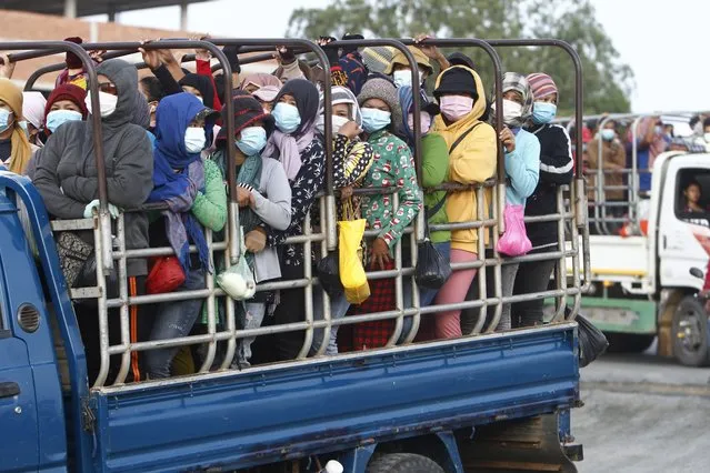 Garment workers stand on the trucks as they head to work outside Phnom Penh, Cambodia, Thursday, May 6, 2021. Cambodia on Thursday ended a lockdown in the capital region. (Photo by Heng Sinith/AP Photo)