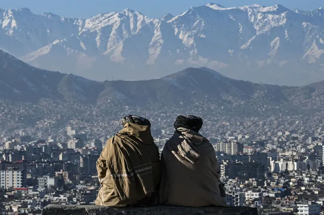 Members of the Taliban sit overlooking the Kabul city at the Wazir Akbar Khan hill in Kabul on January 20, 2022. (Photo by Mohd Rasfan/AFP Photo)