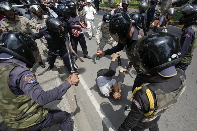 A man tries to protects himself as security forces beat him during the International Workers' Day rally at Freedom Park in Phnom Penh May 1, 2014. Cambodia authorities broke up a protest of garment workers and opposition party supporters on Thursday who rallied to celebrate the International Labor Day despite the government's ban on public assemblies. (Photo by Samrang Pring/Reuters)